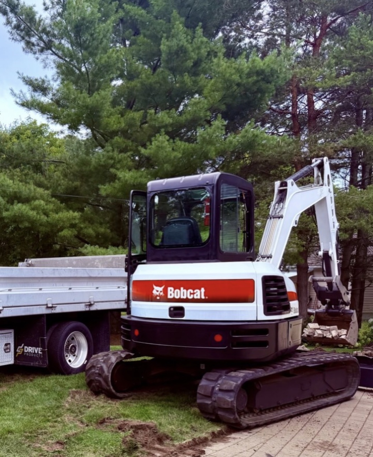 Bobcat E55 excavator parked next to a float trailer on a residential property