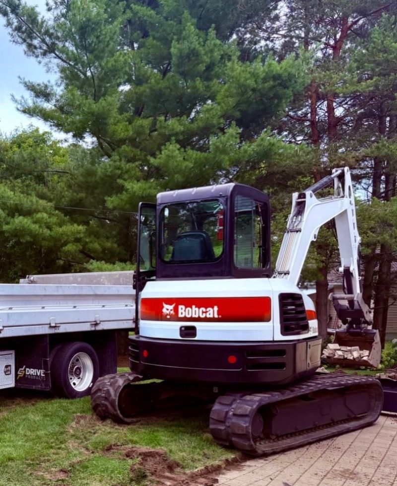 Bobcat E55 excavator parked next to a float trailer on a residential property